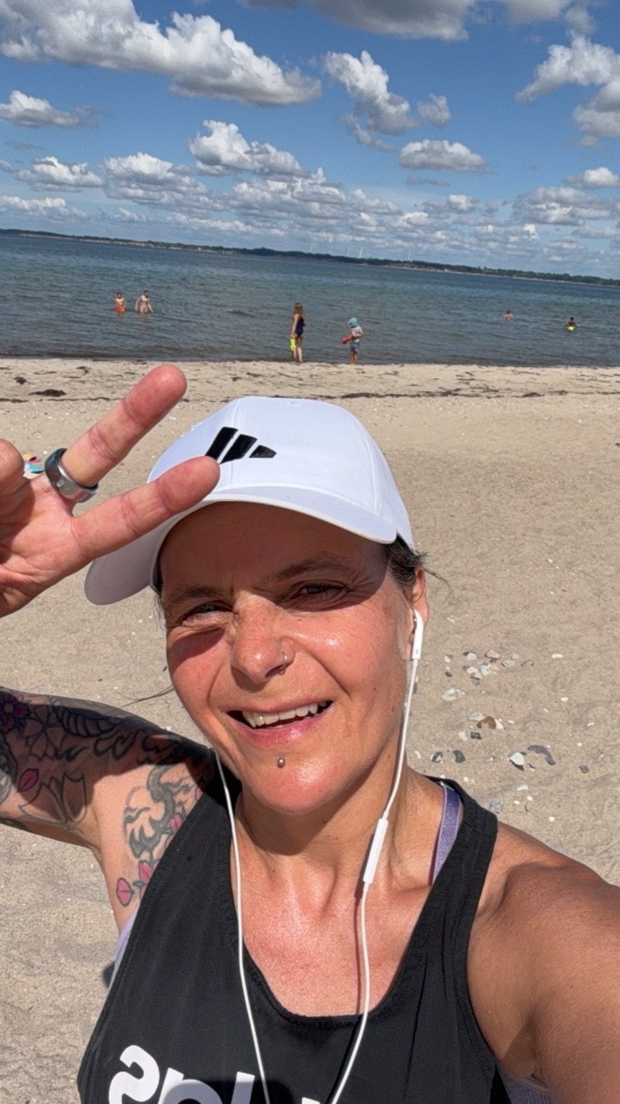 Inga Wiegert am Strand, lachend mit Peace-Zeichen