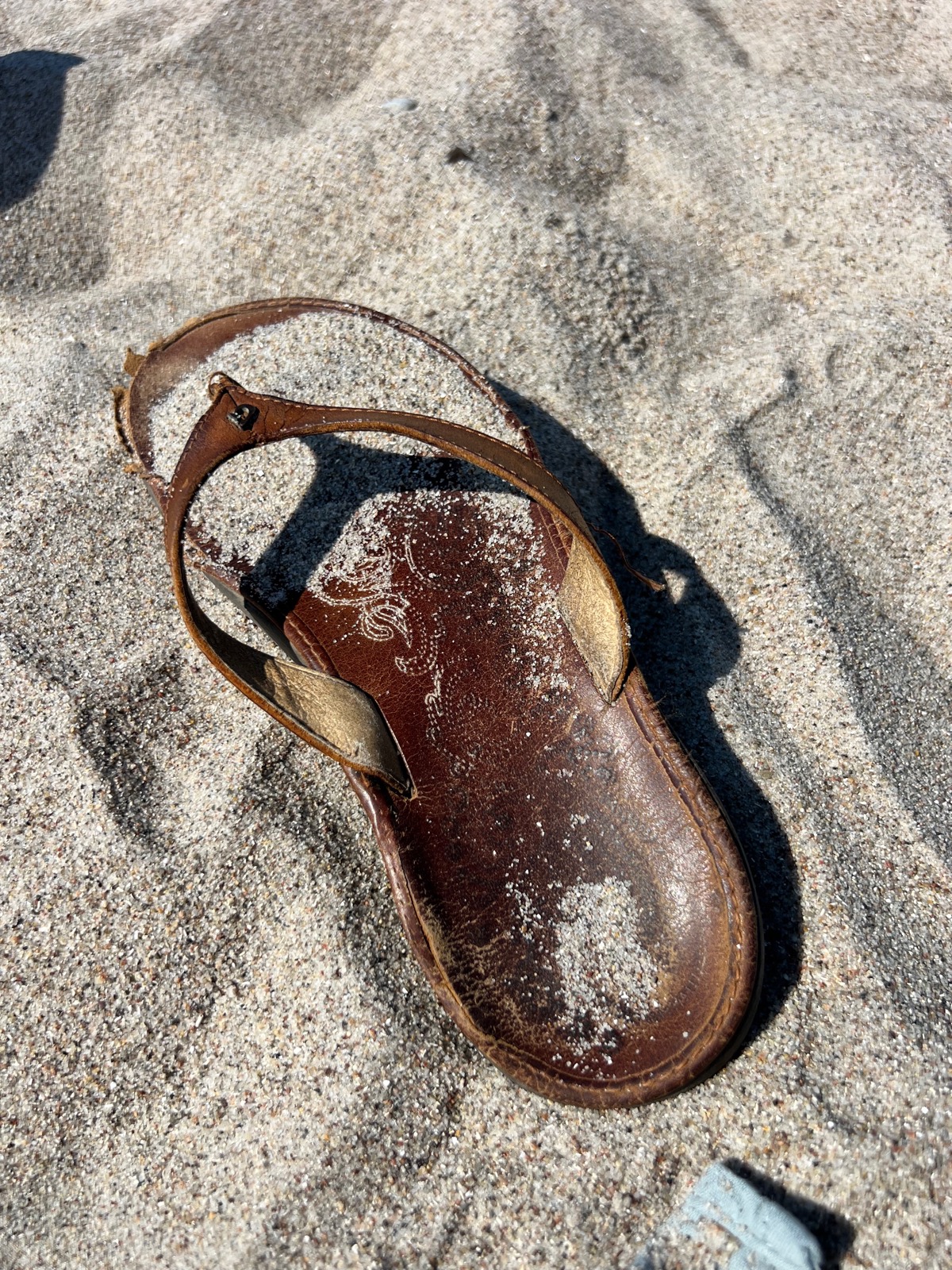 Abgetragene Ledersandale im Sand